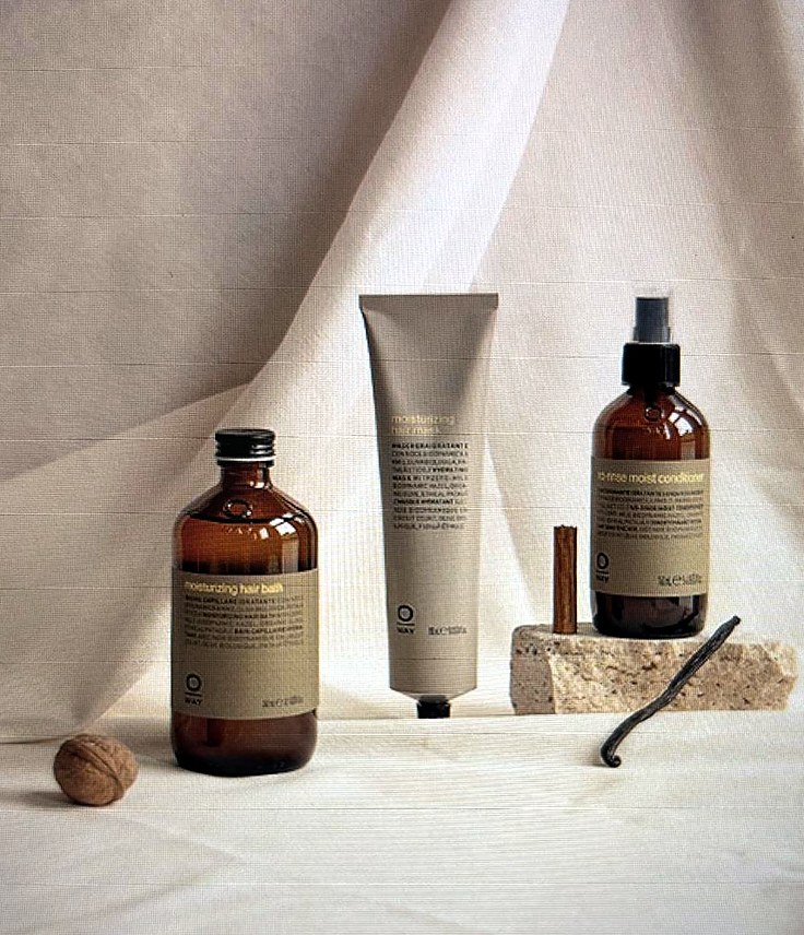 Oway Moisturizing Hair Bath, Moisturizing Hair Mask en No-rinse Moist Conditioner op een linnen doek en travertijnsteen